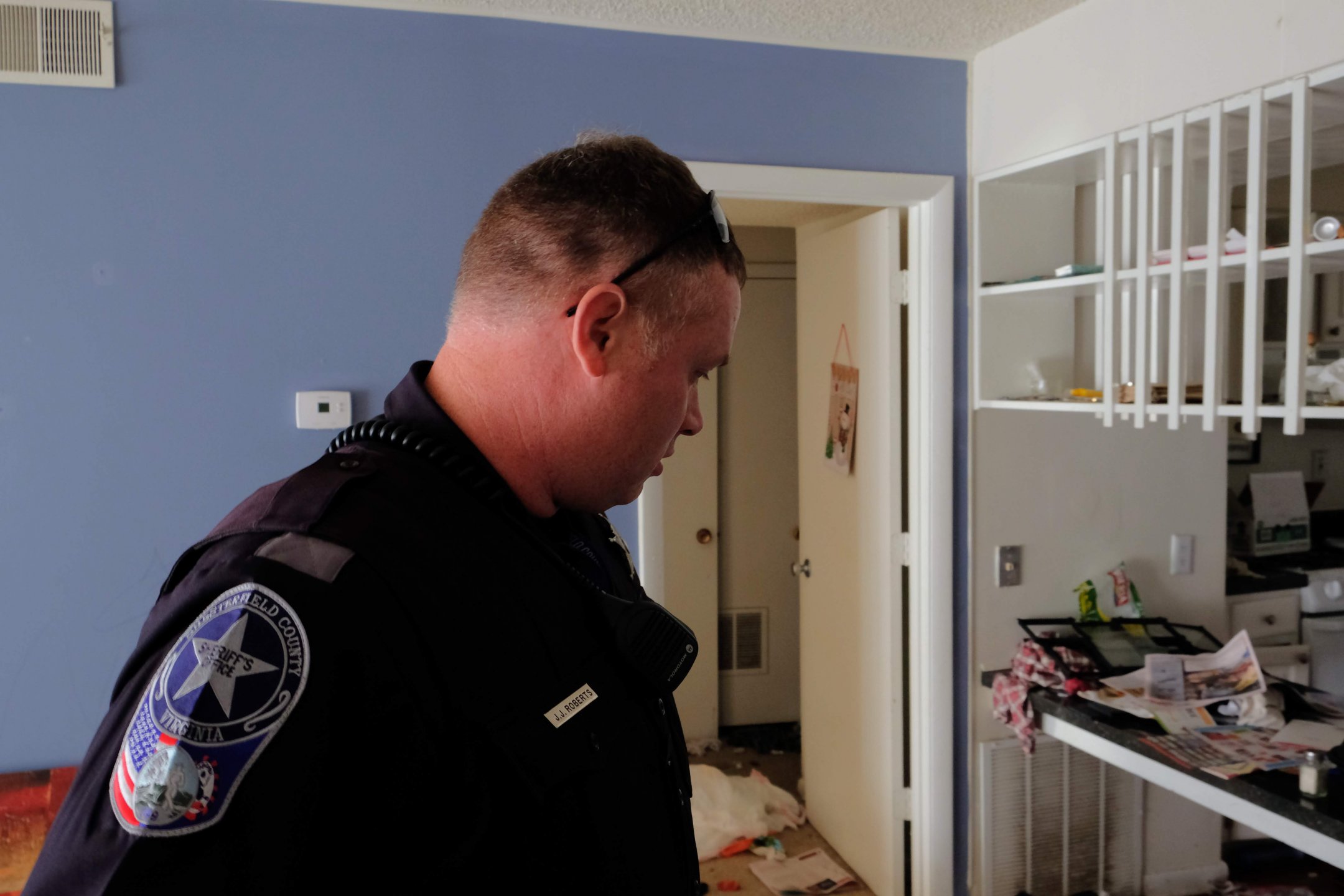 Deputy Roberts surveys an apartment where he’s conducting an eviction. Roberts estimates that tenants have already left in 95% of his evictions, but he does a quick check for people, pets, weapons or drugs they may have left behind. (Photo: Ben Paviour/VPM)
