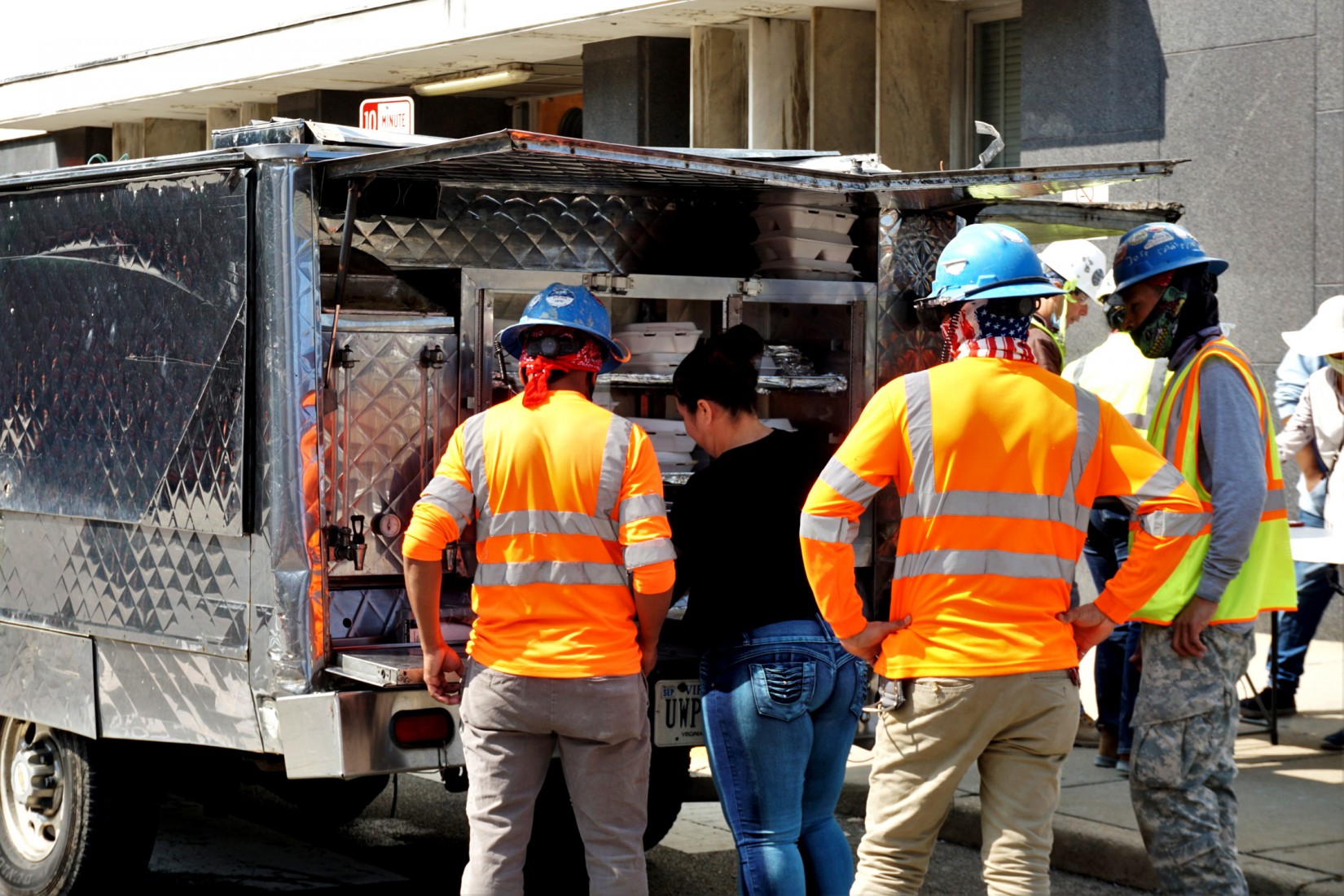 VCU Construction Workers Allege Wage Theft, Exploitation 2 Workers cluster around a food truck. (Photo: Alan Rodriguez Espinoza/ VPM News)
