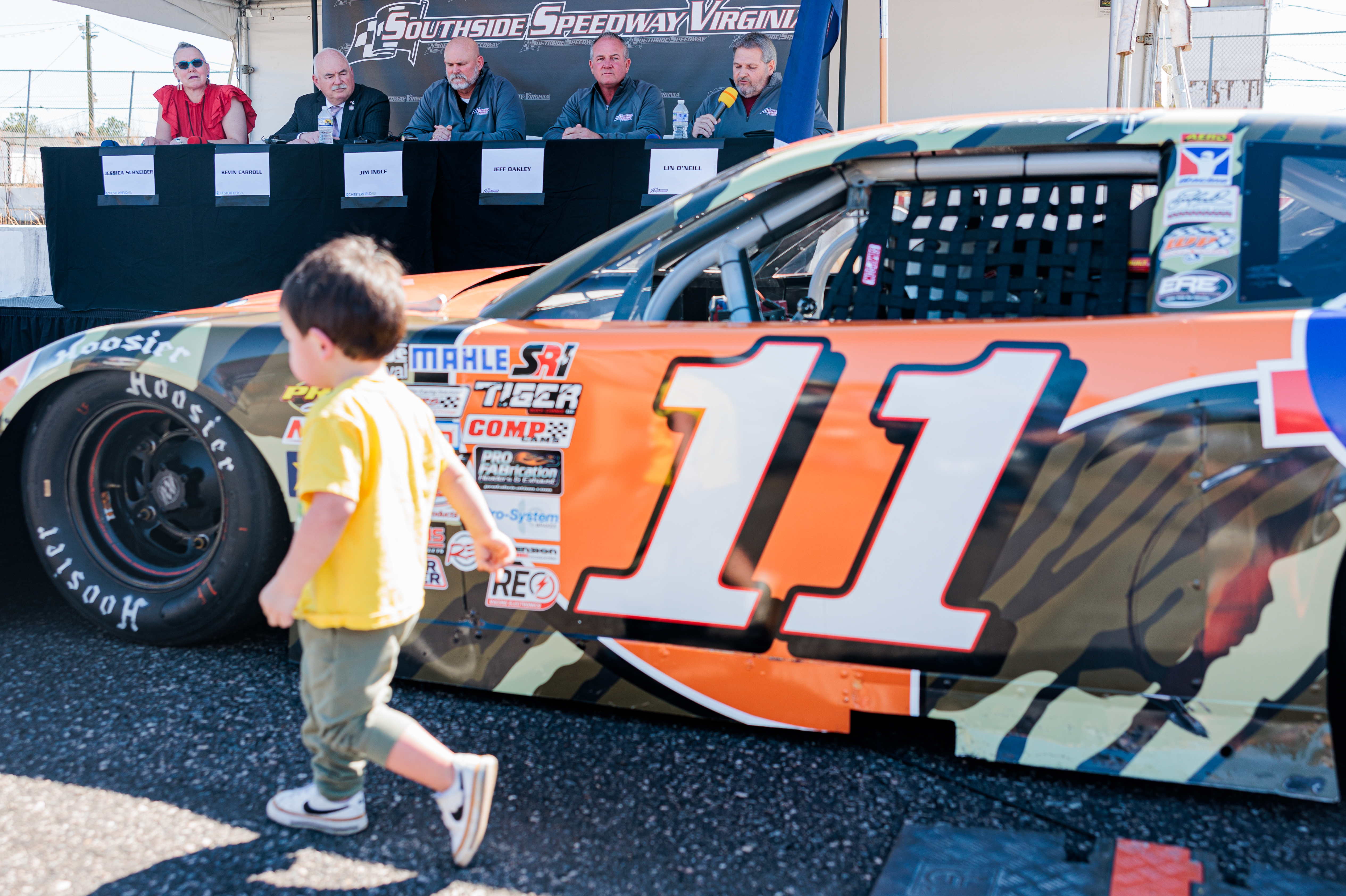 Christian Southworth, 2, inspects the cars as Lin O'Neill (background, right), of Competitive Racing Investments, speaks at a press conference announcing the reopening of the Southside Speedway on Tuesday, March 11, 2025 in Midlothian, Virginia.